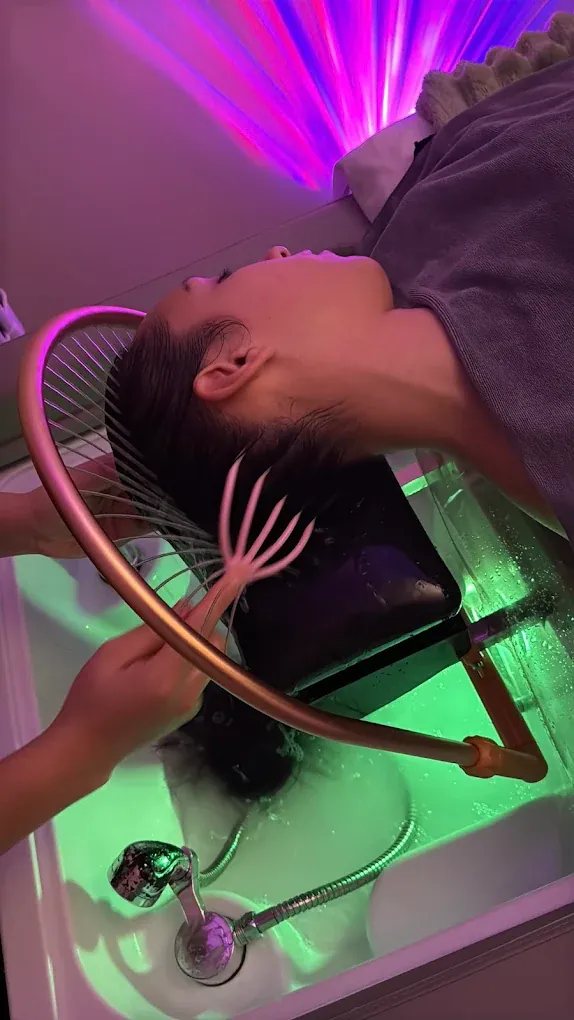 Head spa station glowing under LED light at the Everett studio — a popular add-on after deep tissue