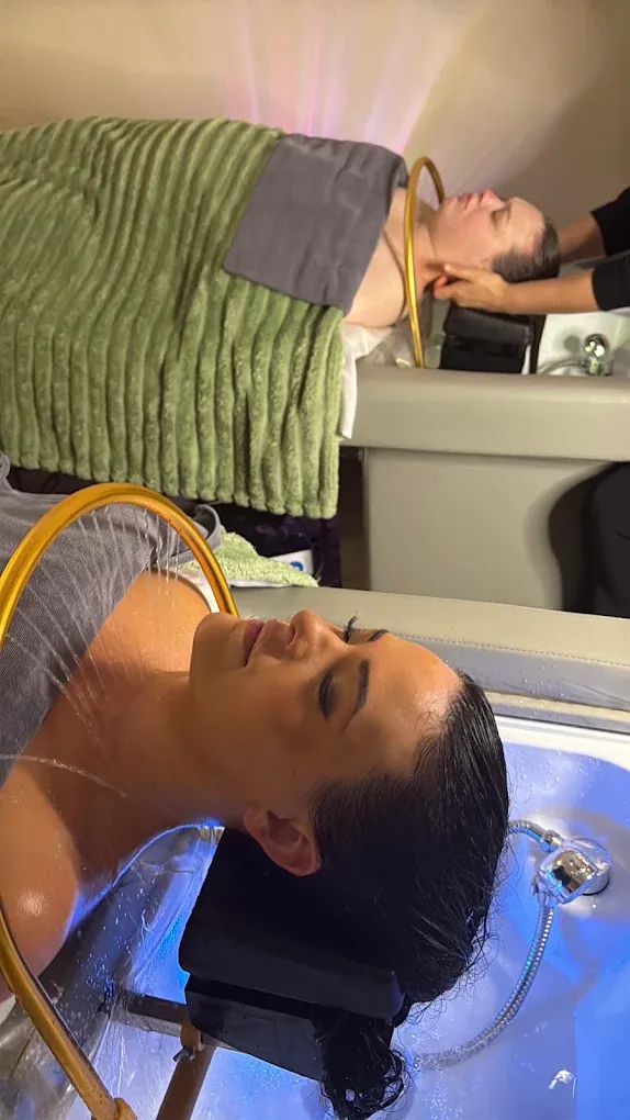 Two guests receiving scalp treatments at adjacent stations in the Everett studio